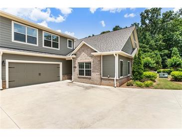 Charming home showcasing a two-car garage, well-manicured landscaping, and a mix of stone and siding accents at 1896 Grove Field Ln # 29, Marietta, GA 30064