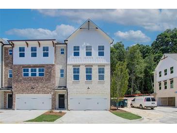 Charming townhouse with a brick and white facade, featuring a two-car garage and well-maintained landscaping at 586 Avondale Park Cir, Decatur, GA 30032