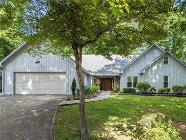Charming home exterior featuring a well-manicured lawn, stone accents, and a double garage at 4212 Burns Heritage Ne Trl, Roswell, GA 30075