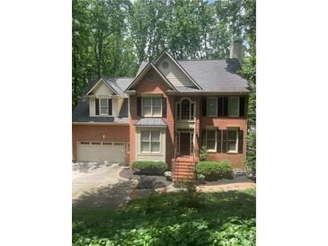 Charming brick home featuring a manicured front yard and an attached two car garage at 1915 Habersham Trce, Cumming, GA 30041