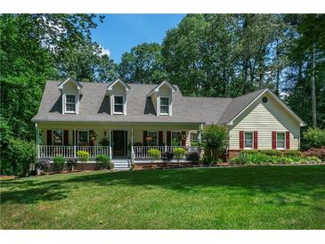 Charming single-Gathering home with a well-manicured lawn and inviting front porch nestled in a lush, wooded landscape at 2050 Lyda Ln, Loganville, GA 30052