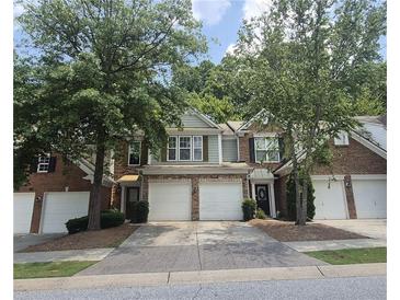 Charming townhome exterior with brick and siding, complemented by a two-car garage and a well-manicured lawn at 2061 Fosco Dr, Duluth, GA 30097