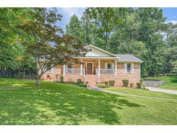 Charming brick home with a well-manicured lawn, inviting front porch and beautiful mature trees providing plenty of shade at 3812 Chattawood Dr, Duluth, GA 30096