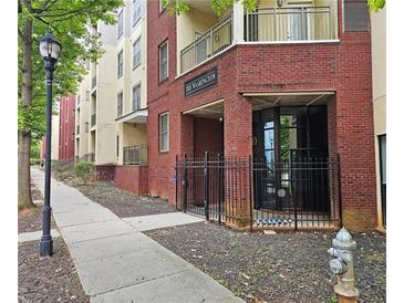 Brick exterior building entrance with black metal gated door and sidewalk with mature tree in view at 870 Mayson Turner Rd # 1207, Atlanta, GA 30314