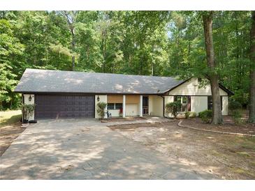 Charming single-story home with a two-car garage and a well-maintained front yard surrounded by mature trees at 225 Hardwood Dr, Covington, GA 30016