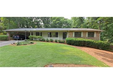 Charming single-story home featuring a well-manicured lawn, carport, and brick accents at 2600 Amberly Dr, Dunwoody, GA 30360