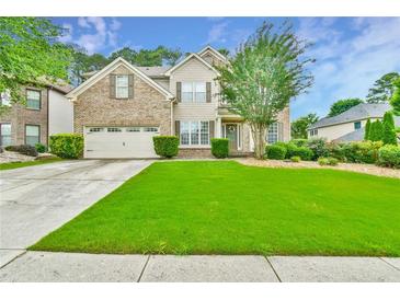 Charming two-story home featuring a manicured lawn, brick facade, and attached two-car garage at 3060 Mccannon Mill Dr, Dacula, GA 30019
