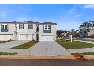 Newly constructed townhomes featuring attached garages and modern architectural details stand on manicured lawns at 329 Heavenly Hollow Pl, Mcdonough, GA 30253