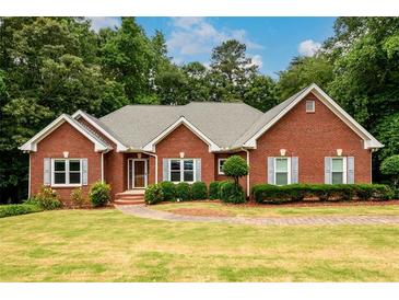 Charming brick home with a well-manicured lawn, beautiful landscaping, and classic gray shutters at 3648 Clark Hill Way, Buford, GA 30519