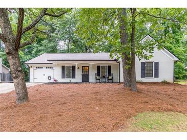 Charming, single-story home with white brick, black shutters, rocking chairs, and manicured landscaping at 2038 Summertown Dr, Norcross, GA 30071