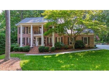 Beautiful brick home featuring a covered porch and well-manicured lawn at 11940 Mountain Laurel Dr, Roswell, GA 30075