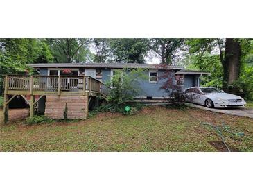 Charming single-story home featuring a wooden deck and a private driveway, nestled among lush greenery at 3220 Memorial Dr, Decatur, GA 30032