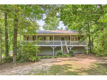 Charming home featuring a spacious front porch and landscaped front yard surrounded by mature trees at 62 Sweetwater Pkwy, Powder Springs, GA 30127