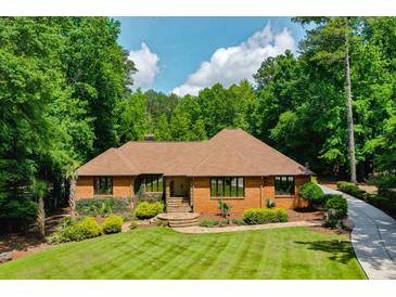 Brick home with well-manicured lawn and mature trees, offering a serene and inviting curb appeal at 1385 Northcliff Trce, Roswell, GA 30076
