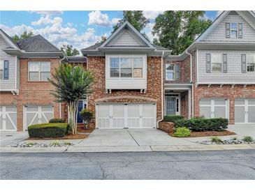 Charming brick townhome featuring a two-car garage, landscaped front yard, and inviting curb appeal at 5207 Merrimont Dr, Alpharetta, GA 30022