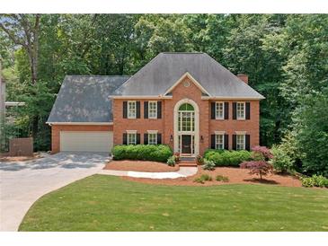 Charming two-story brick home featuring a well-manicured lawn and lush landscaping at 3638 Sope Creek Farm Se, Marietta, GA 30067