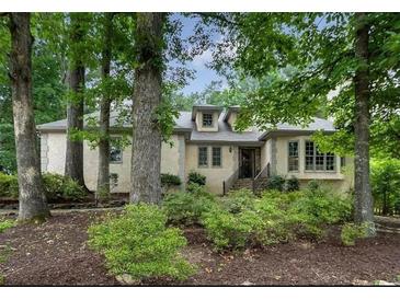 Charming home featuring a tan stucco exterior, complemented by mature trees and lush landscaping at 3261 Stonecreek Ct, Suwanee, GA 30024