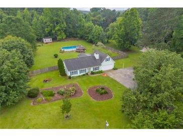 Aerial view of a light green home with a large yard and inground pool surrounded by mature trees at 1789 Brandi Ln, Loganville, GA 30052