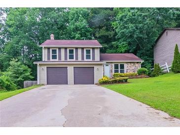 Charming two-story home featuring a two-car garage and well-manicured front lawn surrounded by lush greenery at 765 Martin Rd, Stone Mountain, GA 30088