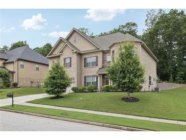 Charming two-story home featuring a well-manicured lawn, lush trees, and a welcoming driveway at 3748 Spring Place Ct, Loganville, GA 30052