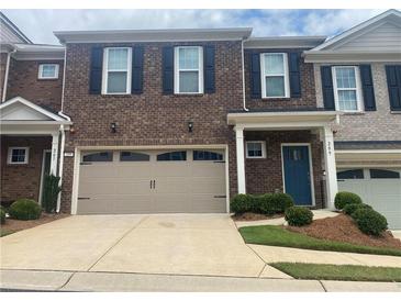 Townhome exterior with brick facade, black shutters, a two-car garage, and manicured landscaping at 209 Ellis Ln, Woodstock, GA 30189