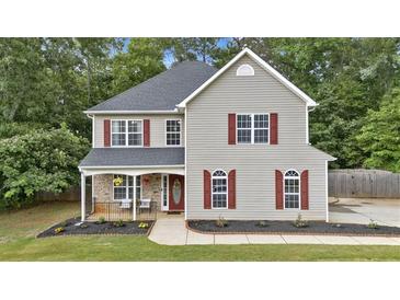 Charming two-story home featuring red shutters, a covered porch, and professionally landscaped front yard at 6350 Summer Pl, Douglasville, GA 30135