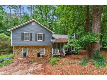Two-story home with blue siding and stone base, surrounded by lush greenery at 4585 Muirwood Cir, Powder Springs, GA 30127