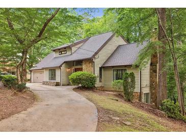 Charming home featuring stone accents, driveway, lush landscaping, and an attached garage nestled amongst mature trees at 6100 Blackwater Trl, Atlanta, GA 30328