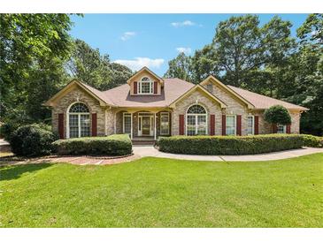 Charming brick home with a lush lawn, beautiful landscaping, and red window shutters under a sunny blue sky at 8110 Lakemont Close, Mcdonough, GA 30253