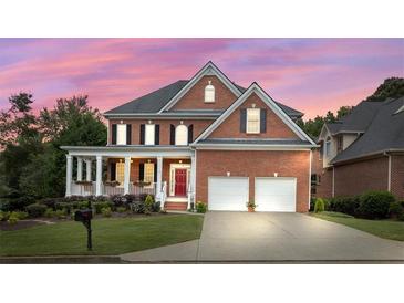Charming two-story brick home with a covered front porch, two-car garage, and landscaped yard at sunset at 1140 Promontory Drive, Marietta, GA 30062