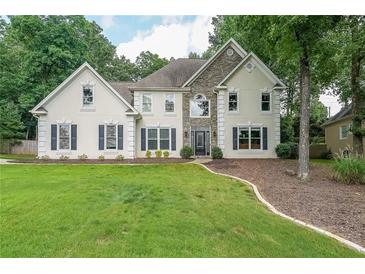 Two-story stucco home with stone accents, manicured lawn, and lush green landscaping at 2970 Chardonnay Ln, Cumming, GA 30041