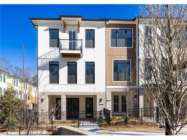 Beautiful three-story townhome with a brick and stucco facade and a small balcony and iron fencing at 350 Olmstead Way # 29, Alpharetta, GA 30022