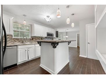 Bright kitchen with white cabinets, island, stainless steel appliances, and modern lighting at 1086 Erie Cir, Stone Mountain, GA 30087