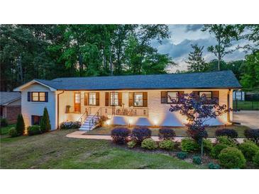 Charming brick home showcasing manicured landscaping and inviting front porch illuminated by accent lighting at 1600 Donna Sw St, Mableton, GA 30126