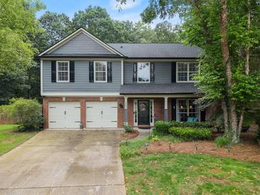 Charming two-story home with a well-manicured lawn, attached garage, and welcoming front porch at 5885 Millstone Dr, Cumming, GA 30028