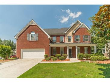 Two-story red brick home featuring a well-manicured lawn and beautiful landscaping at 2479 Mitford Ct, Dacula, GA 30019