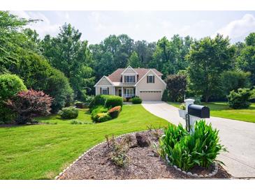 Charming home featuring lush lawn, mature trees, and a neatly manicured garden enhancing curb appeal at 6455 Ivey Meadow Ln, Cumming, GA 30040