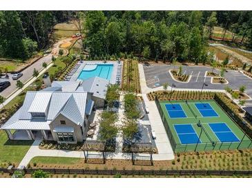 An aerial view of the neighborhood clubhouse with a pool, tennis courts, parking lot, and landscaping at 5330 Keepsake Court, Cumming, GA 30040