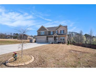 Beautiful two-story home featuring a three-car garage and manicured front yard on a sunny day at 157 Donovan Ave, Locust Grove, GA 30248