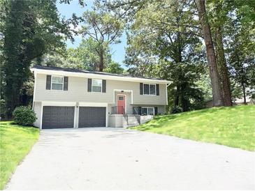 Charming split-level home with a two-car garage, freshly painted exterior, and well-manicured front lawn at 6965 Kimberland Gardens Ln, Lithonia, GA 30058