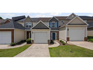 Charming townhome featuring an attached garage, a blue front door, and manicured landscaping at 1510 Paramount Ln, Sugar Hill, GA 30518
