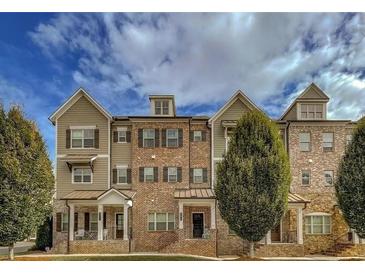Charming townhome featuring a brick and siding exterior, complemented by a well-manicured lawn and lush landscaping at 209 Snapdragon St, Woodstock, GA 30188