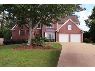 Charming two-story brick home with a well-manicured lawn and a two-car garage on a sunny day at 2720 Stillwater Lake Ln, Marietta, GA 30066