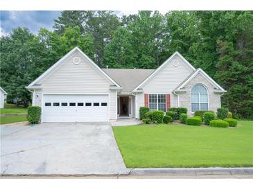Charming single-story home with well-maintained lawn and two car garage and manicured shrubs at 2407 Cove Lake Way, Lithonia, GA 30058