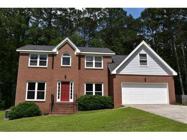 Charming two-story brick home with a well-manicured lawn and a two-car garage, nestled among mature trees at 1471 Ashwood Way, Lawrenceville, GA 30043