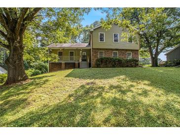 Charming split-level home with a brick facade and inviting front porch nestled among mature trees at 4819 Elam Rd, Stone Mountain, GA 30083
