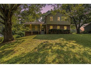 Charming two-story home featuring brick accents and a welcoming covered porch with beautiful landscaping and mature trees at 4819 Elam Rd, Stone Mountain, GA 30083