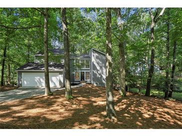 Charming two-story home with a gray exterior and a two-car garage nestled in a wooded lot at 545 Woodman Pl, Roswell, GA 30076