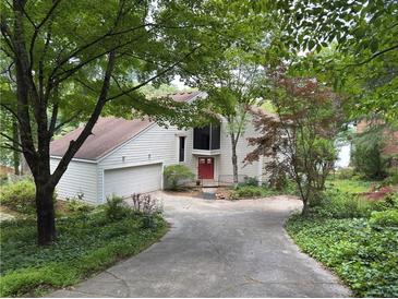 Inviting home featuring a red front door, two car garage and mature trees enhancing the curb appeal at 3836 Loch Highland Ne Pkwy, Roswell, GA 30075