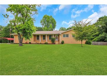 Charming brick home with a well-manicured lawn and mature trees, creating a welcoming curb appeal at 3332 Oak Grove Rd, Loganville, GA 30052